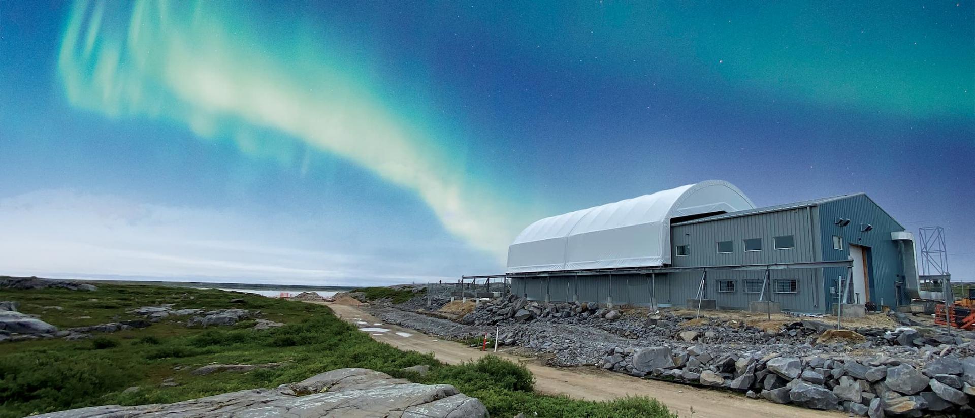 Image of large metal building and aurora borealis  in the background